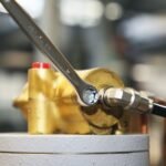A Beta Tools 7/16 combination wrench in use on a brass hydraulic fitting, emphasizing accuracy and smooth torque application. Get it at Wrenchers.com.