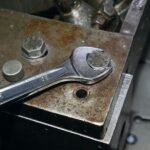 A Beta Tools 1/2-inch combination wrench gripping a hex bolt on a weathered industrial block, showcasing rugged durability and fit accuracy. Get it at Wrenchers.com.