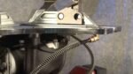 Close-up of the Coats RC-45A bead sealing jet assembly, showing the metal turntable underside, mounting hardware, and coiled air hose with a brass fitting