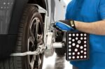 Close-up of a technician attaching an AC400-style wheel alignment clamp and target plate to a vehicle wheel.