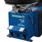 Front view of the Hofmann Monty 1675-SS tire changer showing foot pedal controls and SmartSpeed-equipped cabinet